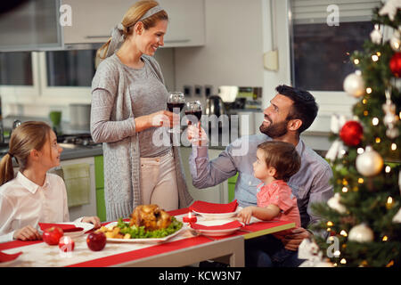 Wife with husband toasting with red wine during gala Christmas dinner Stock Photo