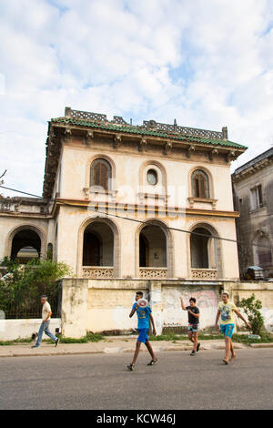 Kids playing frisby in front of a Decaying mansion, Vedado, Havana, Cuba Stock Photo