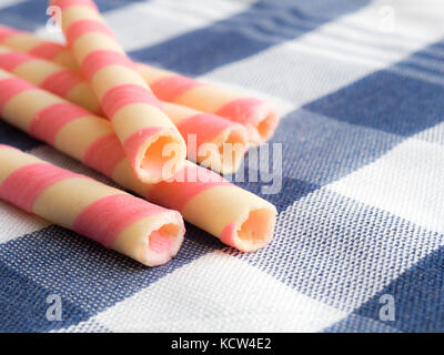 pink striped wafer rolls on blue plaid tablecloth. Stock Photo