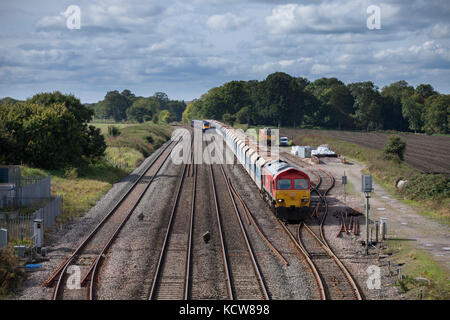 A First Great Western  high speed train overtakes a DB Cargo freight train at Woodborough between Pewsey & Westbury, Wiltshire UK Stock Photo