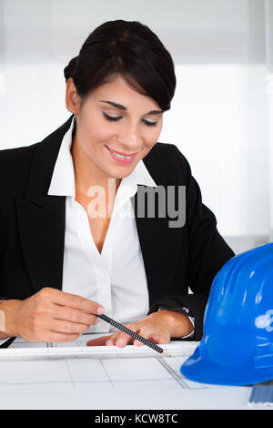 Young Happy Female Architect Working On Blue Print In Office Stock Photo