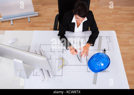 Young Happy Female Architect Working On Blue Print In Office Stock Photo