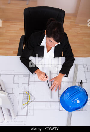 Young Happy Female Architect Working On Blue Print In Office Stock Photo