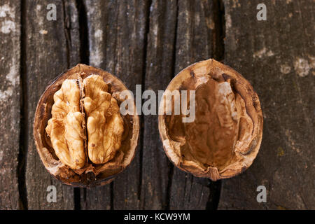 Two nuts, one open and one closed on an old wooden table Stock Photo