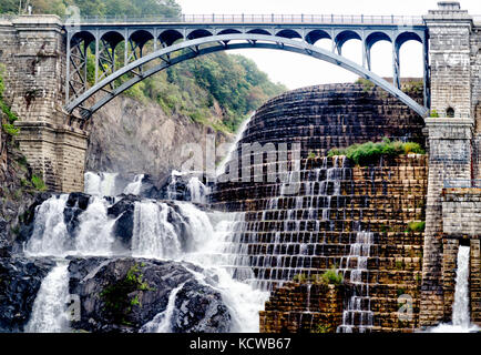 An old dam that stops the lake from flooding over is created by both natural and man made means with a bridge to span the distance of the ravine. Stock Photo