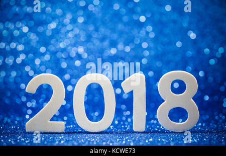 New year 2018 white wood number on blue paper with glitter lights. Mock up banner space for display or montage of product, business presentation. Stock Photo