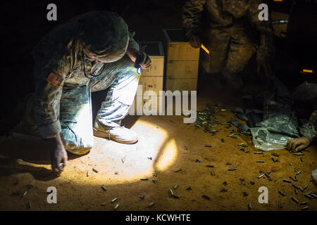 U.S. Soldiers assigned to the 1050th Transportation Battalion and 151st Expeditionary Signal Battalion, S.C. Army National Guard collect spent brass after the crew-served weapons familiarization night training at Fort Jackson, S.C., Sept. 15, 2016.  30 Soldiers from multiple transportation and signal companies train on dismounted security drills and crew-served weapons in preparation for their qualification next summer and to stay current with convoy security. (U.S. Air National Guard photo by Tech. Sgt. Jorge Intriago) Stock Photo