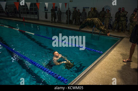 South Carolina Army National Guard Sgt. Tyler Watkins, an assistant operations NCO with the 678th Air Defense Artillery Brigade, 263rd Army Air and Missile Defense Command, removes the outer layer of his uniform as a requirement for the swimming portion of the the German Armed Forces Badge for Military Proficiency tryouts at Fort Jackson, S.C., Jan. 30, 2017. This was the first iteration where the tryouts were incorporated into the 2017 Best Warrior Competition. (U.S. Air Force photo by Staff Sgt. Marianique Santos) Stock Photo