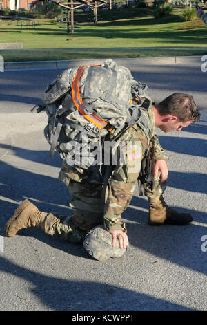 A Soldier from the 1st Battalion 118th Infantry Regiment, 218th Maneuver Enhancement Brigade, South Carolina National Guard, takes a knee after completing a six-mile ruck march as part of the battalion-level Best Warrior Competition selection board in North Charleston, South Carolina, Oct. 23, 2016. The selection board for the competition consisted of four voting members evaluating candidates' skills and knowledge in areas such as the Army Physical Fitness Test, land navigation, self-aid and buddy care, Army programs and current events. One Soldier and one non-commissioned officer, along with  Stock Photo