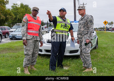 U.S. Army Pvt. 1st Class Bradley Burgess, C Company, 1st Battalion 118th Infantry Regiment, South Carolina Army National Guard, and City of North Charleston Patrolman 1st Class Giovanni Brown explains the details for a traffic control point  to Staff Sgt. Keven Pickering of the 108th Public Affairs Det. in North Charleston, South Carolina, Oct. 5, 2016.  Hurricane Matthew peaked as a Category 4 hurricane in the Caribbean and was projected to pass over the southeastern U.S., including the S.C. coast. Approximately 1,400 S.C. National Guard Soldiers and Airmen were activated Oct. 4, 2016, to sup Stock Photo