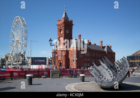 Ferris Wheel and  Pierhead Building at Cardiff Bay, with industrial relic as sculpture in foreground. Cardiff Bay, Cardiff, UK Stock Photo