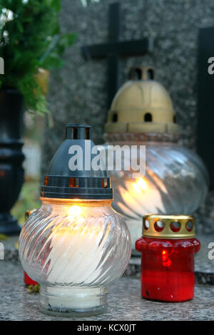 Votive candles lit on tombstone Stock Photo