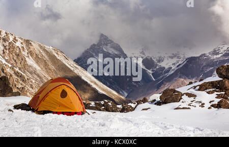 Yellow dome tent glowing on the snow with mountain background in Chile Stock Photo