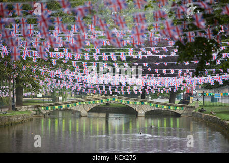 Stone bridge over the Windrush River decorated with knitted cycling vests and Union Jack flags for the Tour of Britain cycle race Stock Photo