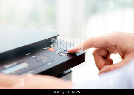 Hand press button on panel of printer. printer scanner laser office copy machine supplies start concept Stock Photo