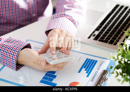 Man using mobile phone while working on laptop. Working with financial statement document Stock Photo