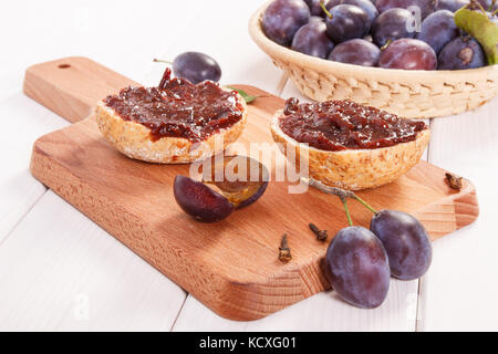 Fresh prepared sandwiches with plum jam on wooden cutting board, concept of delicious breakfast Stock Photo