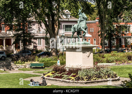 Quebec City 13.09.2017: Bronze statue of Sancta Joanna D arc - Joan of Arc stands as a war memorial in a colorful garden on a sunny day Stock Photo