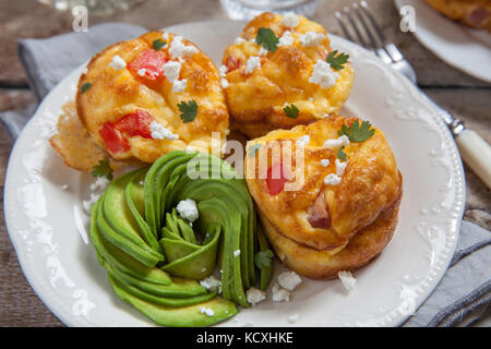 Delicious egg muffins with ham, cheese, avocado, feta and vegetables Stock Photo