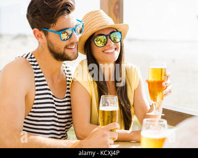 Friends having fun and drinking a cold beer at the beach bar Stock Photo