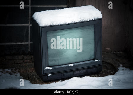 Old tv on street in winter with snow Stock Photo