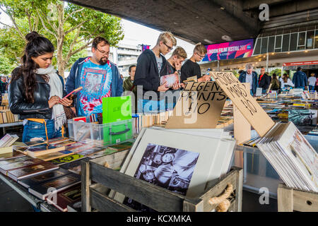 People browsing range of books and prints at South Bank / Southbank book market, under Waterloo Bridge next to the River Thames, London, England, UK. Stock Photo