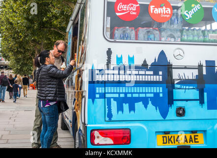 A middle aged couple buying ice cream cornets from an ice cream seller van parked on South Bank, London, England, UK. Stock Photo