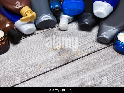 Men's cosmetics background. Various face and body care cosmetic products for men laid out as semicircular frame on old wooden planks. Copy space Stock Photo