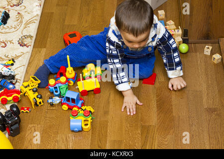 boy sitting on the floor and playing with colored children's t cars Stock Photo