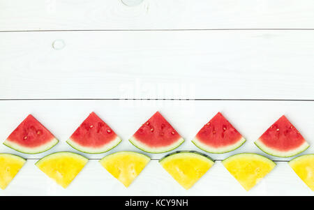 Red and yellow watermelon slices on wooden sticks on a white wooden background. Flat lay, top view, copy space Stock Photo