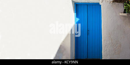 Classic home and architecture on mediterranean islands featuring a blue door and whitewashed walls. Stock Photo