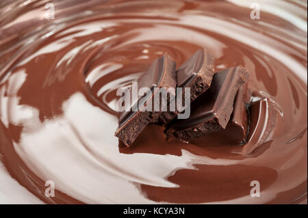 Melted pieces of dark chocolate bar in glossy splash Stock Photo