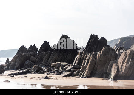 Dark stone on a beach with incoming tide, Pembrokeshire , UK Stock Photo