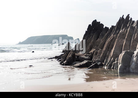 Dark stone on a beach with incoming tide, Pembrokeshire , UK Stock Photo