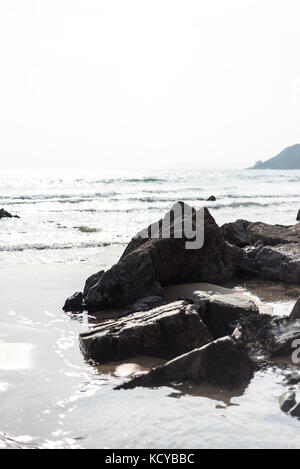 Dark stone on a beach with incoming tide, Pembrokeshire , UK Stock Photo