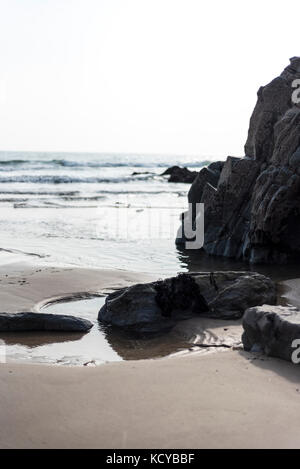 Dark stone on a beach with incoming tide, Pembrokeshire , UK Stock Photo