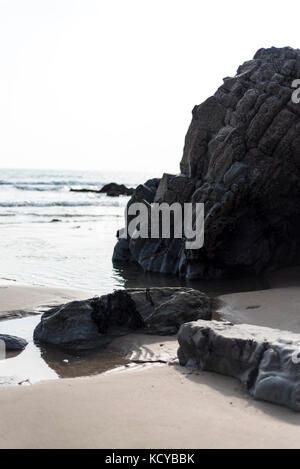 Dark stone on a beach with incoming tide, Pembrokeshire , UK Stock Photo