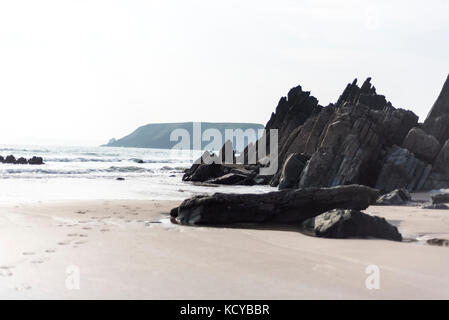 Dark stone on a beach with incoming tide, Pembrokeshire , UK Stock Photo