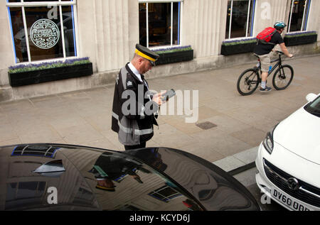 traffic warden logging car registraton details or issuing parking ticket, Merseyside, England Stock Photo