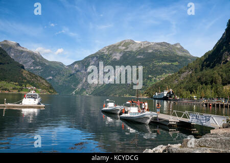 GEIRANGER, NORWAY - AUGUST 13, 2011: Tourists stand on a pier near the pleasure boats. Tours of the Geirangerfjord Stock Photo