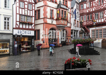 A wet, rainy day at the town of Bernkastel-Kues, in the Mosel Valley, Germany. The tourists have umbrellas to protect from the rain. Stock Photo