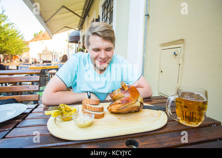 Young man eating smoked pork leg meat and drinking beer Stock Photo