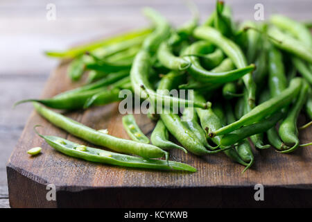 Green beans on wooden cutting board. Go green concept Stock Photo