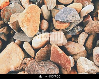 Old stony pavement from natural gravel, dry rounded stones, Traditional building materials, small colorful pebbles. Stock Photo