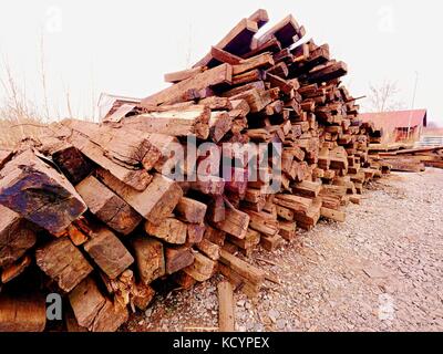 Terrible smell pile of extracted old wooden ties. Old oiled used oak railway sleepers stored after big reconstruction of old railway station. Stock Photo