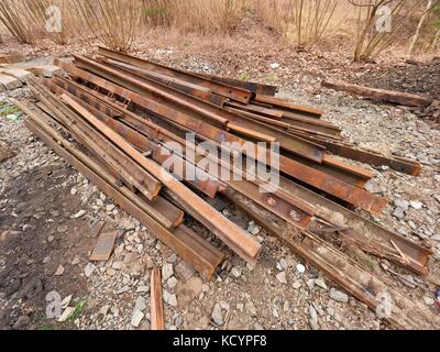 Pile of used rusty rails. Stock of steel rails at old closed railway station.  Metal material is waiting for transport to steel foundry for recycling Stock Photo