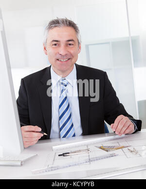 Portrait Of Mature Architect Male With Blueprint In The Office Stock Photo