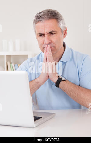 Thoughtful Businessman Working On Laptop At Home Stock Photo