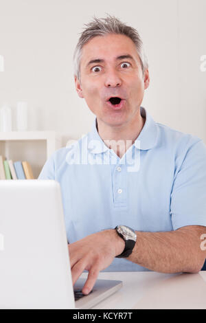 Portrait Of Excited Businessman Working On Laptop Stock Photo