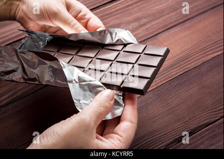 Chocolate bar in wrapper in the hands. Top view. Stock Photo
